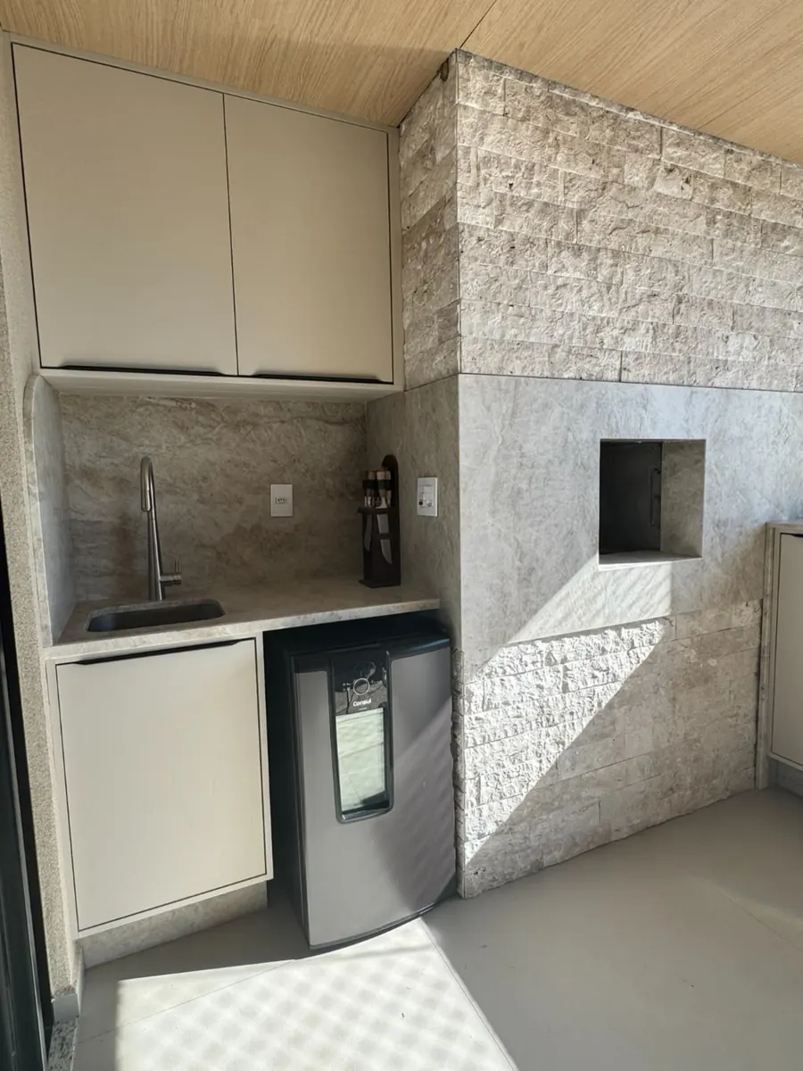 Área gourmet com bancada e parede em pedra